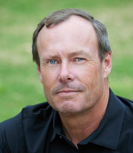 Close-up portrait of a man with a neutral expression against a blurred green background