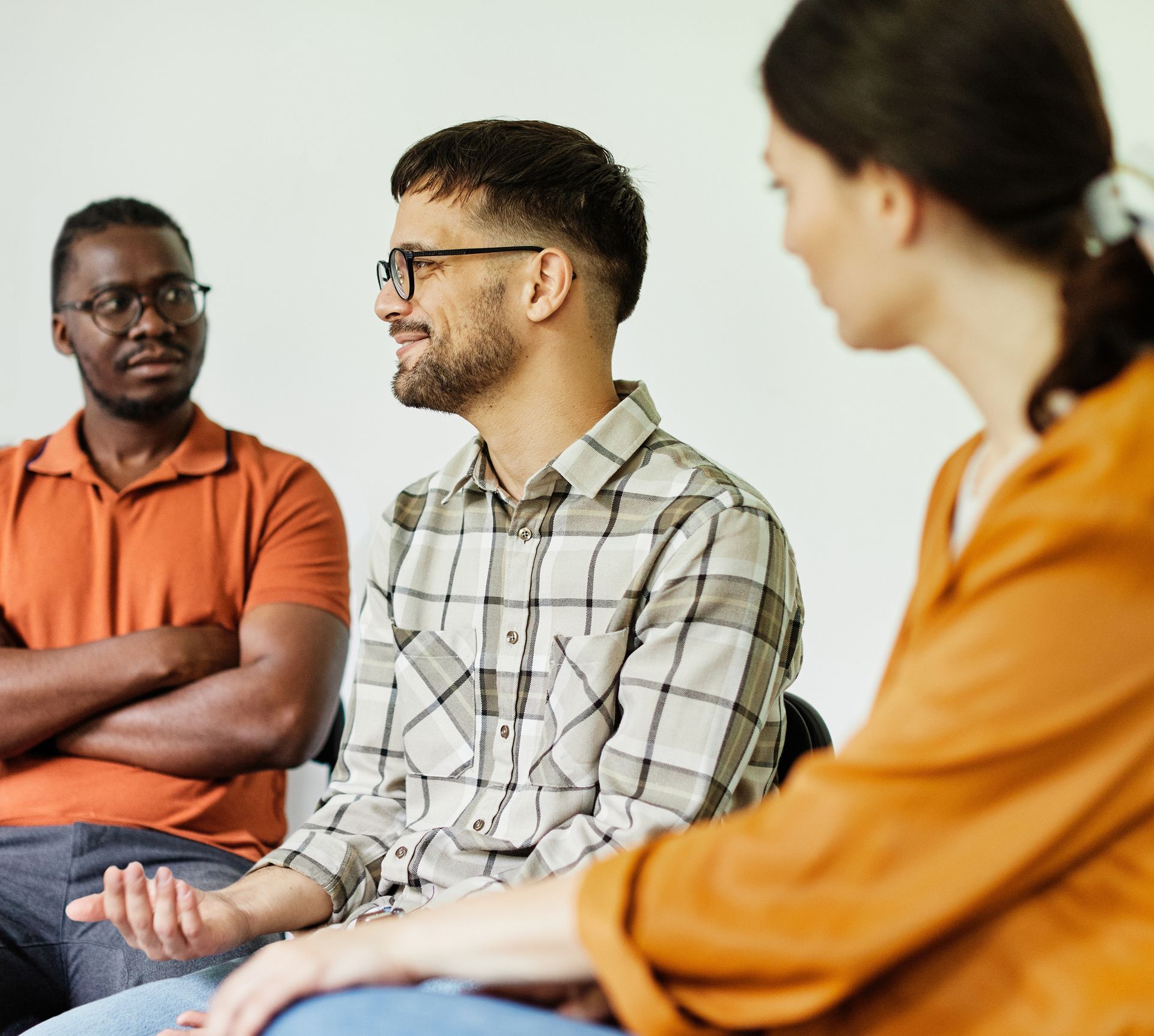 Three people seated in a discussion, one speaking while the others listen attentively.