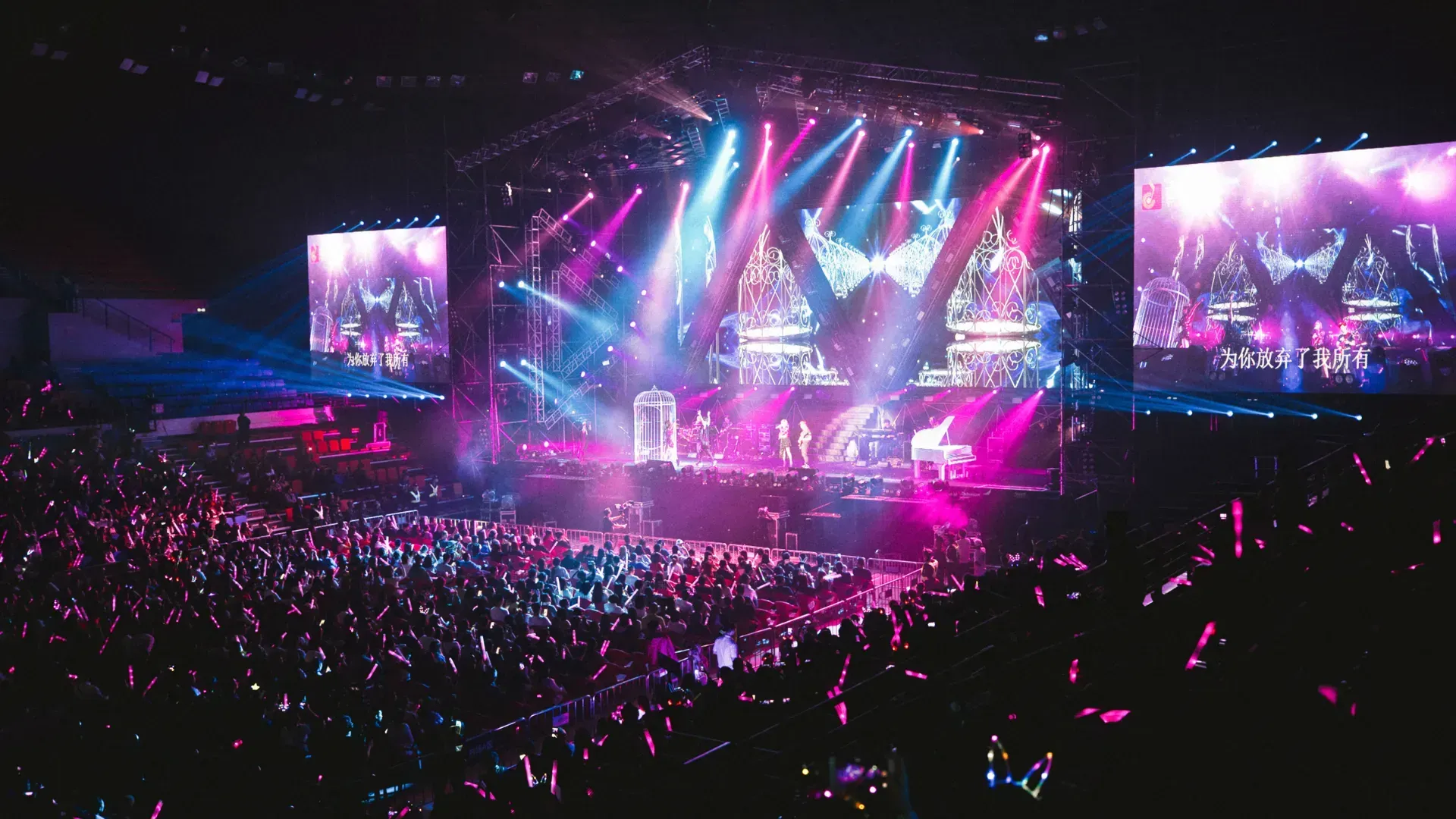 A crowd of people are standing in front of a stage at a concert.