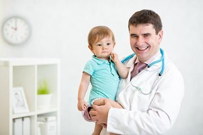 A doctor is holding a baby in his arms.