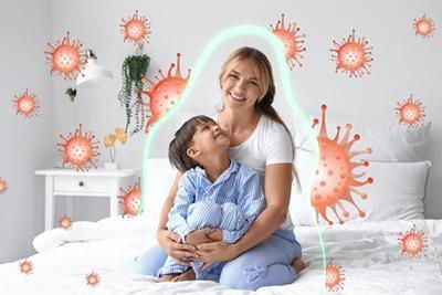 A woman and a child are sitting on a bed surrounded by viruses.