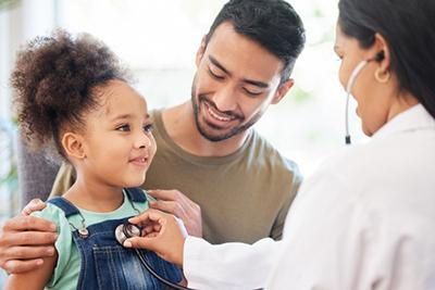 A little girl is being examined by a doctor with a stethoscope.