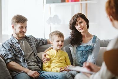 A family is sitting on a couch talking to a counselor.