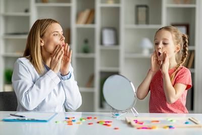 A woman and a little girl are sitting at a table with a mirror.