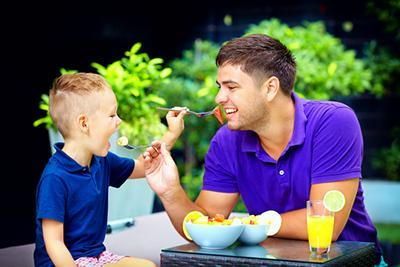 A man and a boy are sitting at a table eating food.