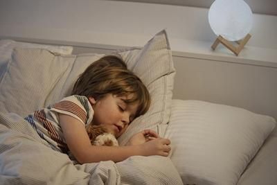 A little girl is sleeping in a bed with a teddy bear.
