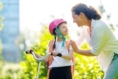 A woman is talking to a little girl on a scooter.