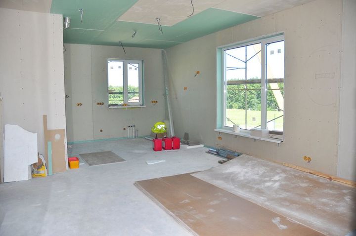 Partially renovated room with unfinished walls, tools, and large windows overlooking greenery