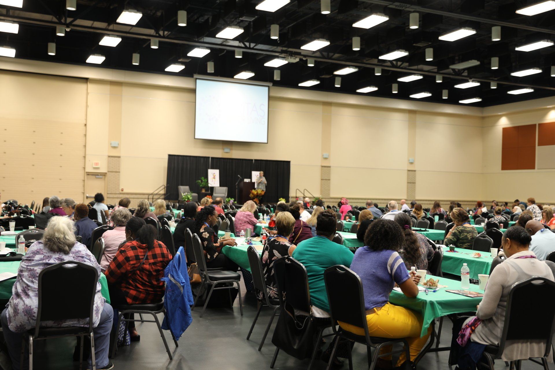 A large group of people are sitting at tables in a large room.