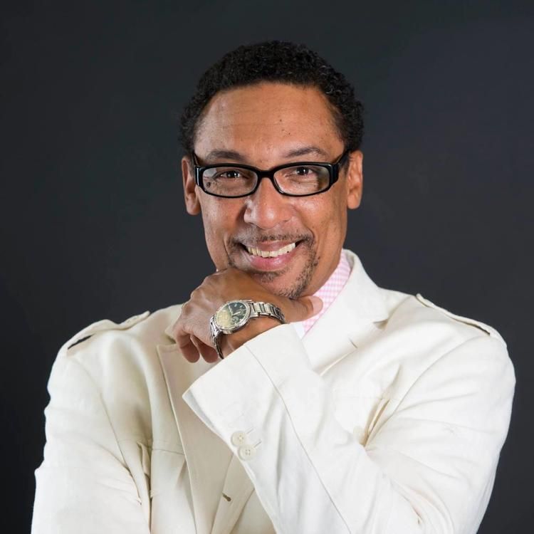 A man wearing glasses and a watch is smiling for the camera