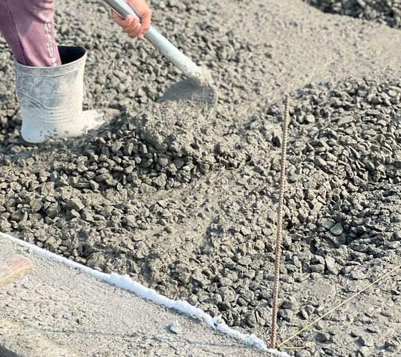 A person is pouring concrete with a shovel.