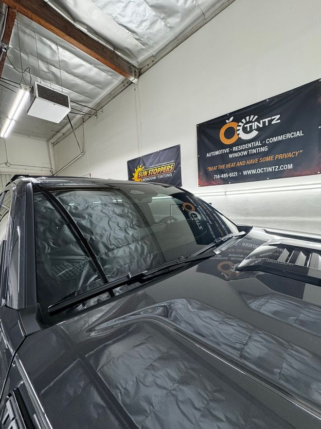 Black car with tinted windows in a shop; banners for 