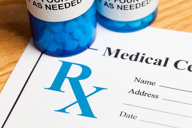 Medical prescription form with a blue Rx symbol and pill bottles on a desk