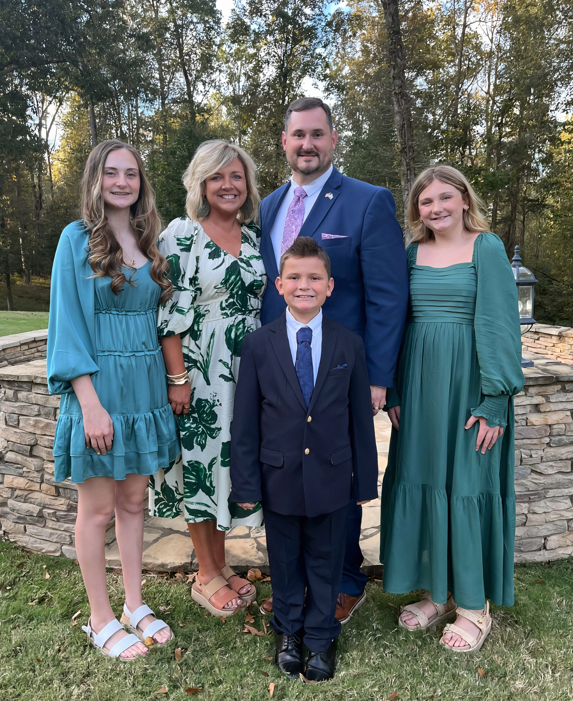 A family posing for a picture in front of a stone wall.