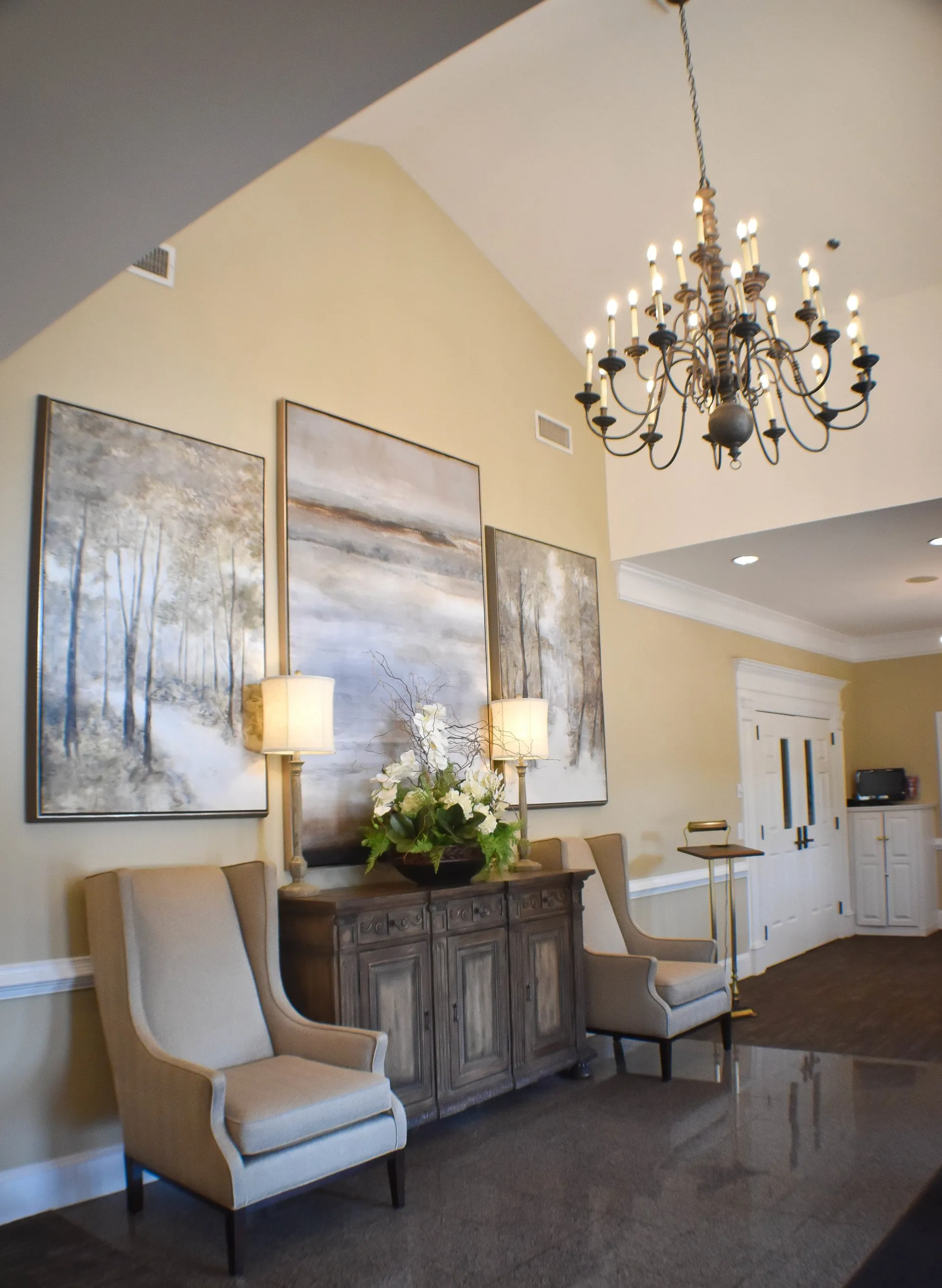 A living room with chairs and a chandelier hanging from the ceiling