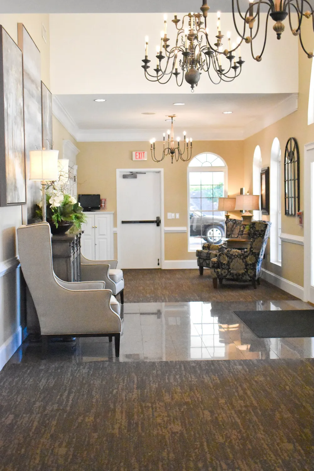 A living room with chairs , a chandelier and a door.