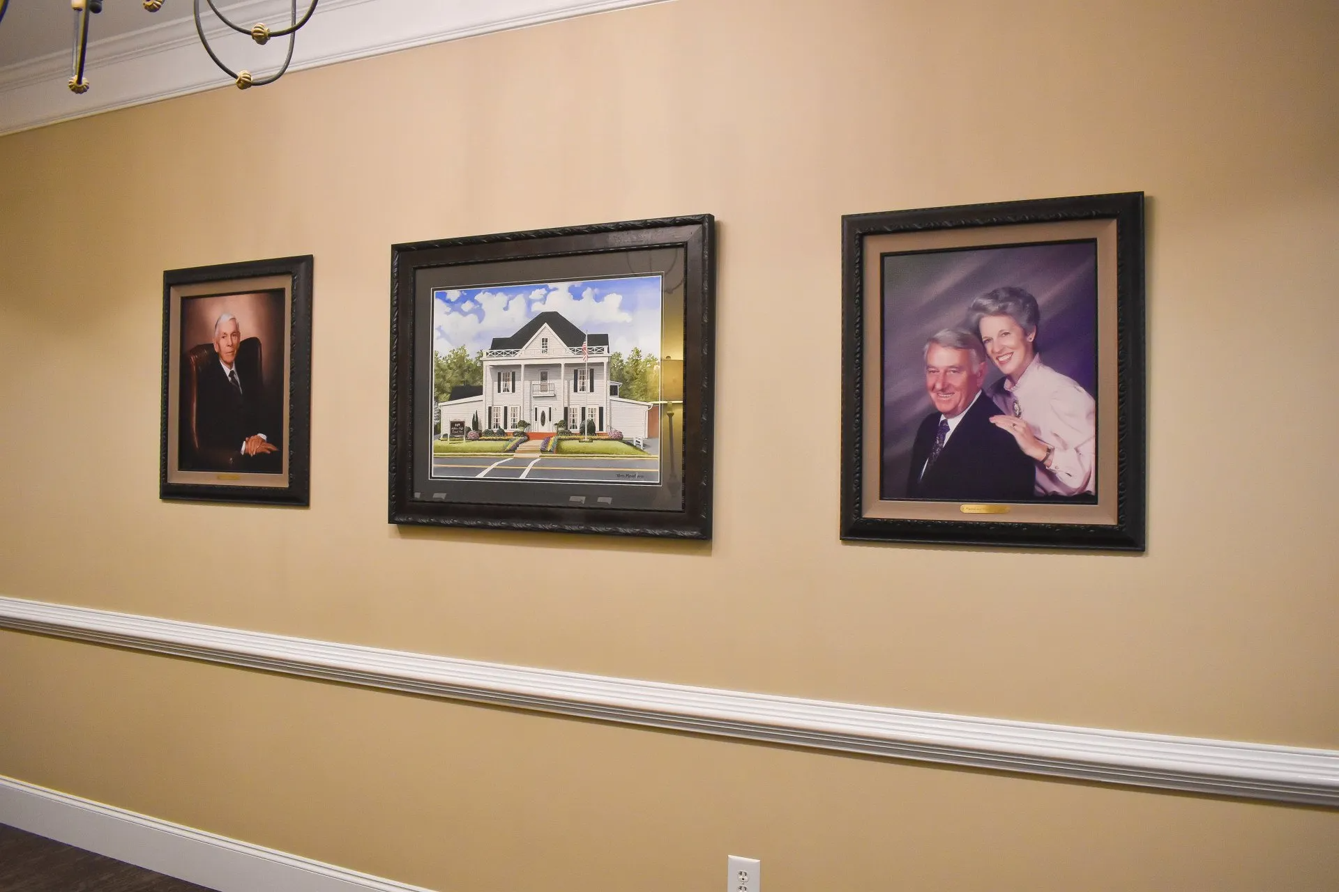 Three framed pictures are hanging on a wall in a hallway.