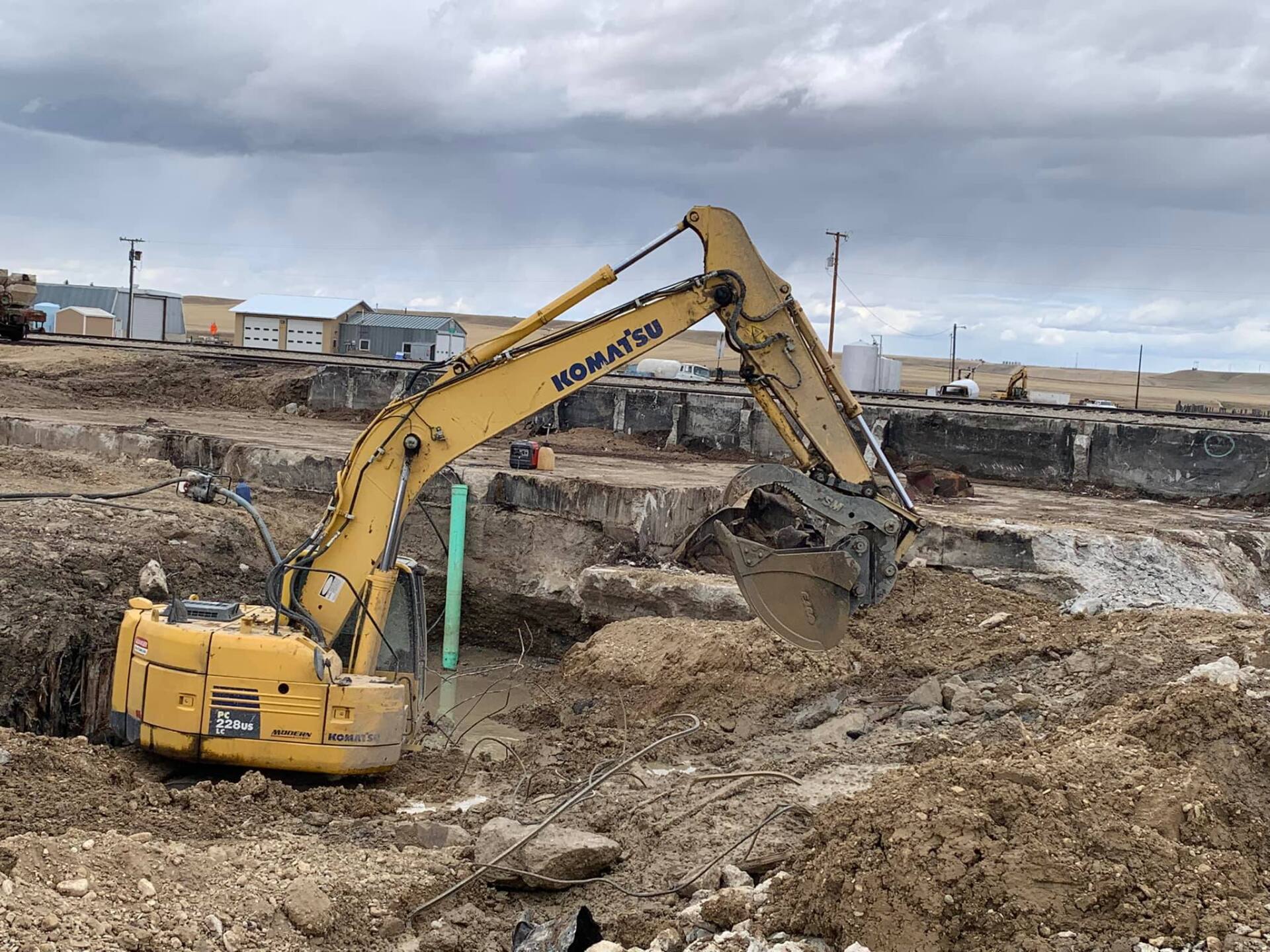 Yellow Komatsu excavator digging in a construction site on a cloudy day.