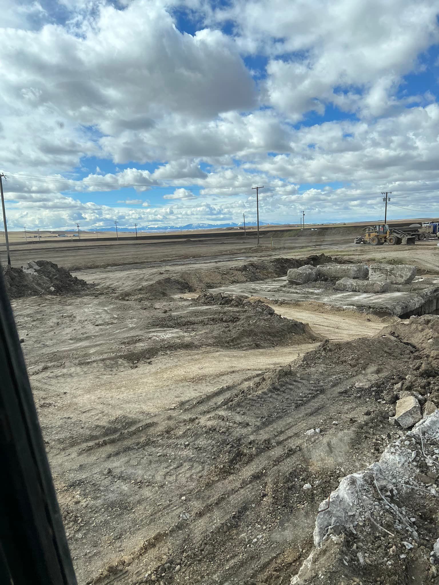Construction site with excavated earth under a cloudy sky.