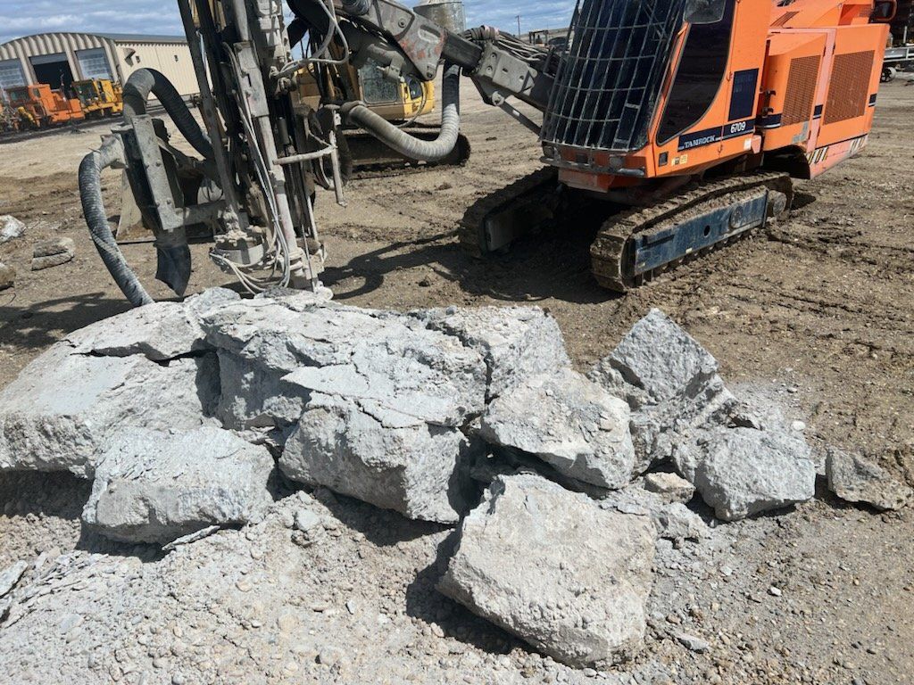 Orange machine breaking up rocks on a construction site.