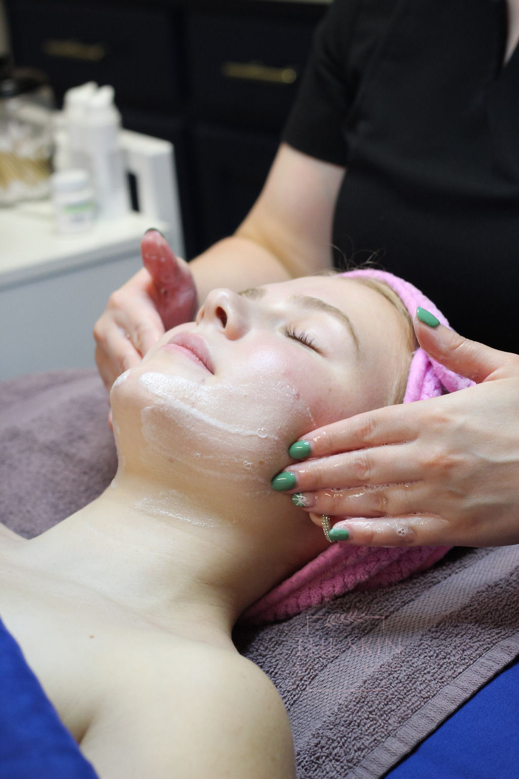 A woman is getting a facial treatment at a beauty salon.