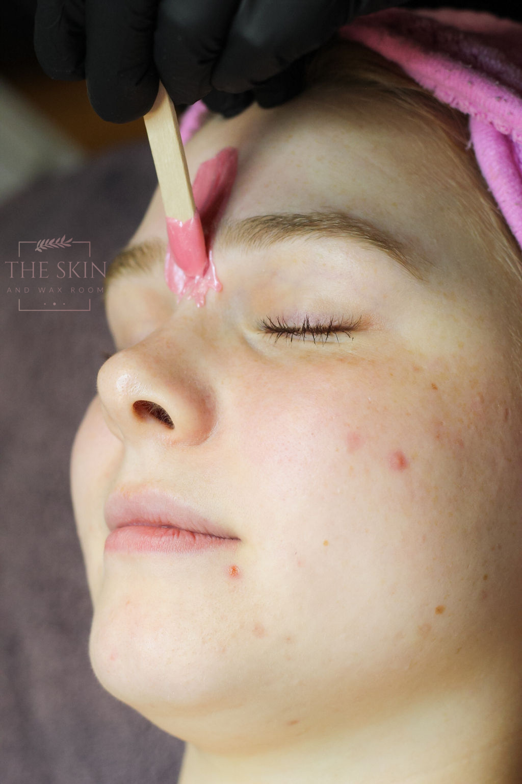 A woman is getting her eyebrows painted with a brush.
