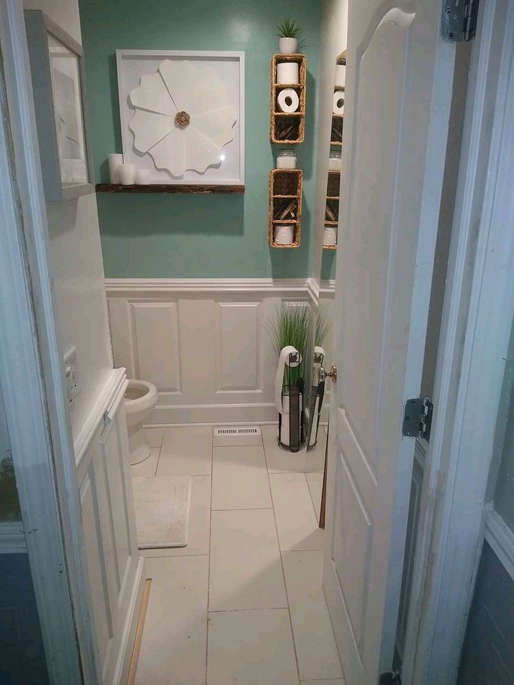 Narrow hallway bathroom with mint-green walls, white wainscoting, and a small wall shelf with decor.