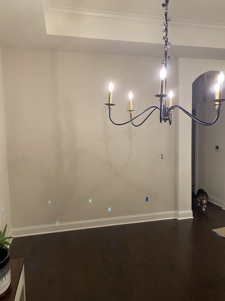 Empty beige dining room with dark wood floors and a black chandelier lit by candles