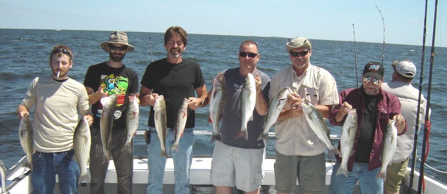 A group of men standing on a boat holding fish