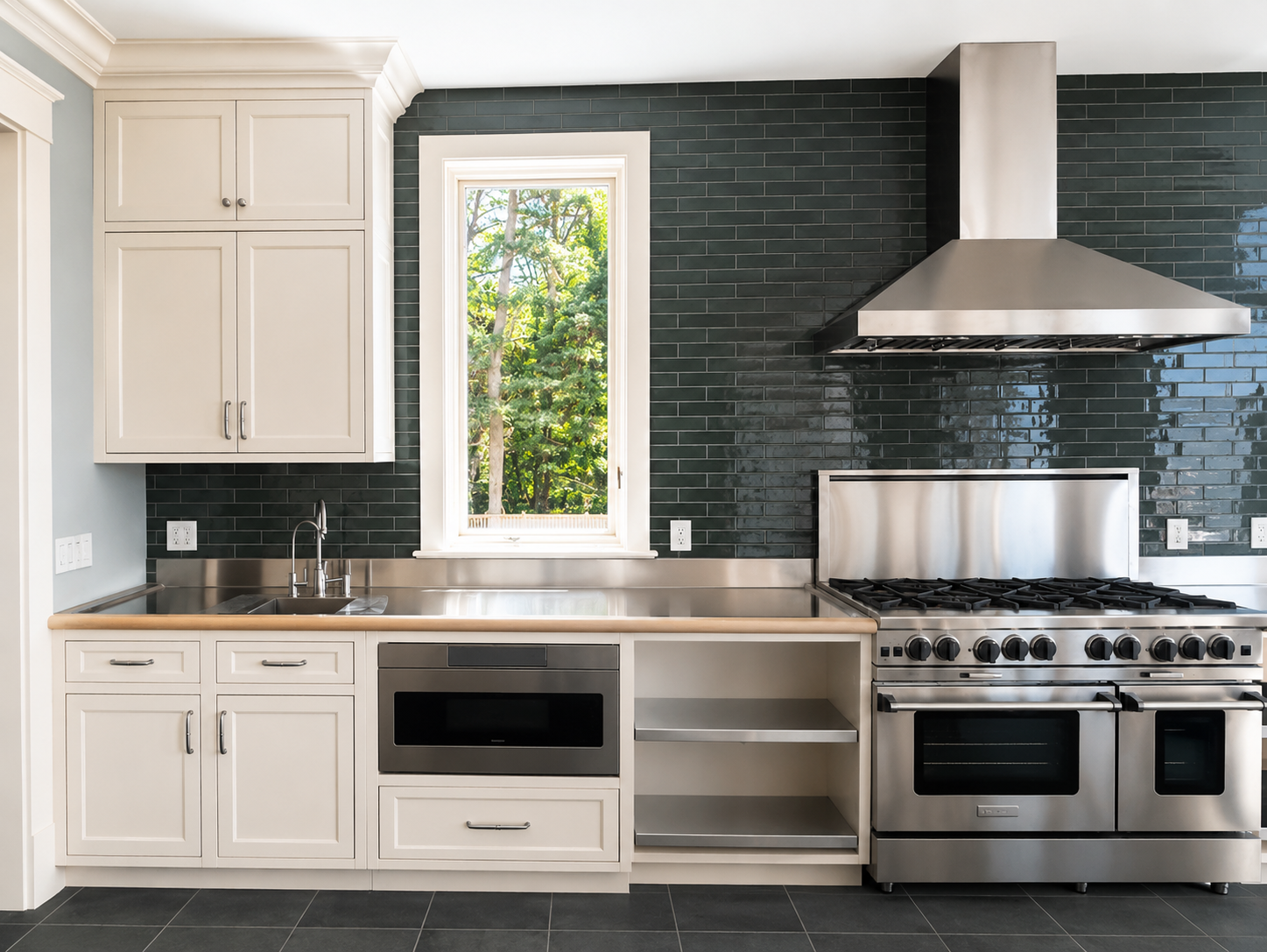 Modern kitchen with white cabinets, black backsplash, stainless steel appliances, and a window above the counter.