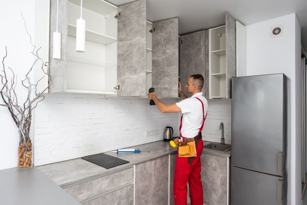 Worker installing cabinets in a modern gray-and-white kitchen