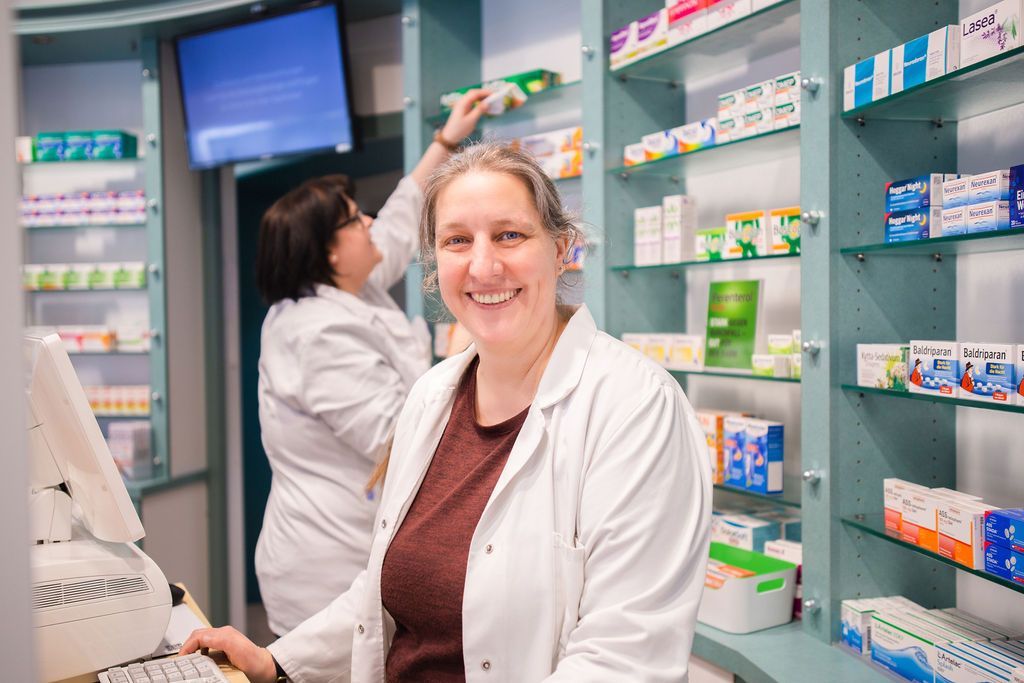 Eine Frau steht in einer Apotheke vor einem Computer.