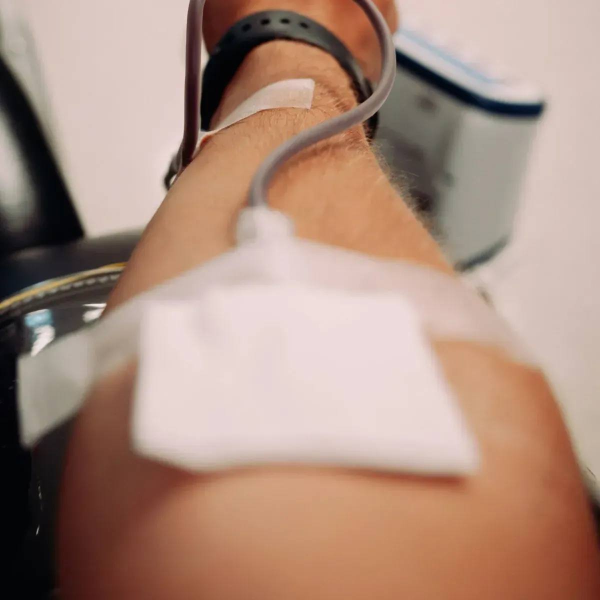 Arm extended with IV line and adhesive bandage in a clinical setting