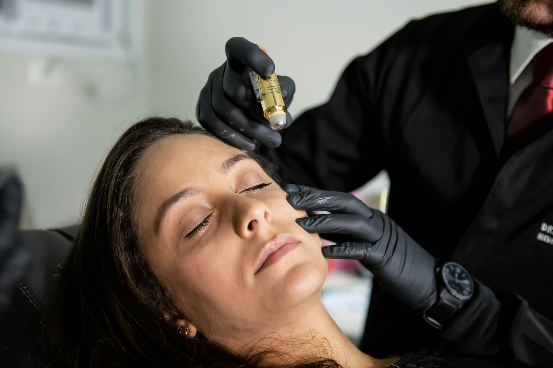 Gloved hand inserting acupuncture needles into skin, close-up on treatment site