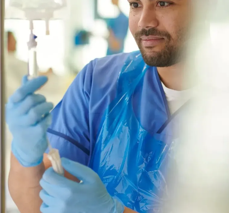 Laboratory technician in blue gloves holding a test tube beside IV equipment