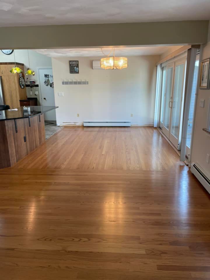 An empty living room with hardwood floors and sliding glass doors.