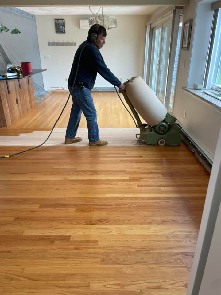 A man is sanding a wooden floor with a machine.
