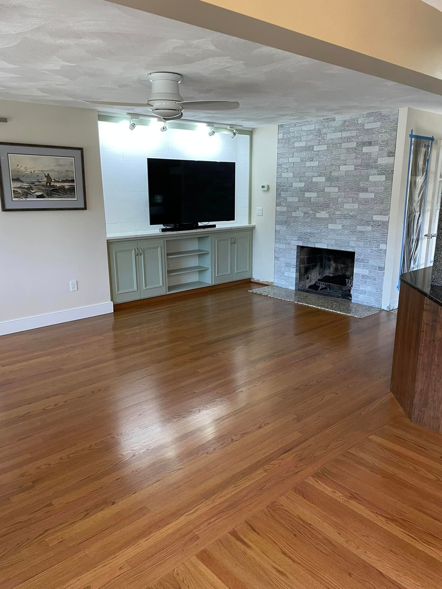 A living room with hardwood floors , a fireplace and a flat screen tv.