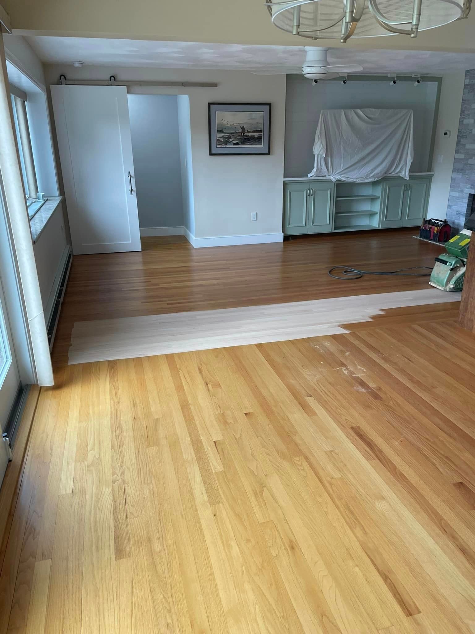 A wooden floor is being painted in a living room.