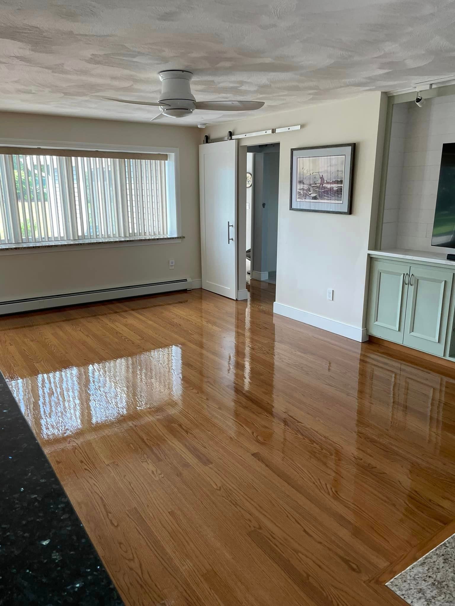 A living room with hardwood floors and a ceiling fan.