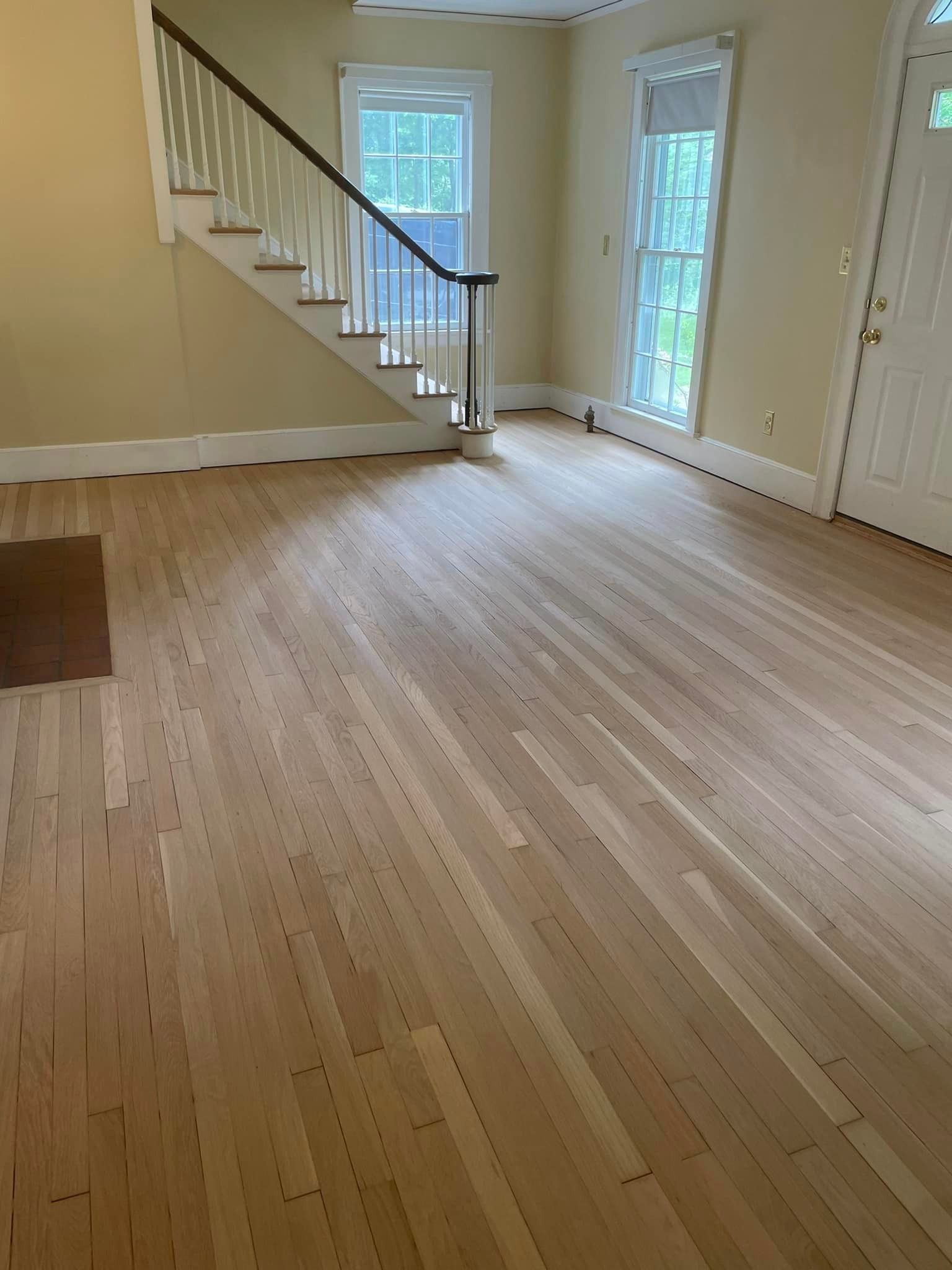 A living room with hardwood floors and stairs in a house.