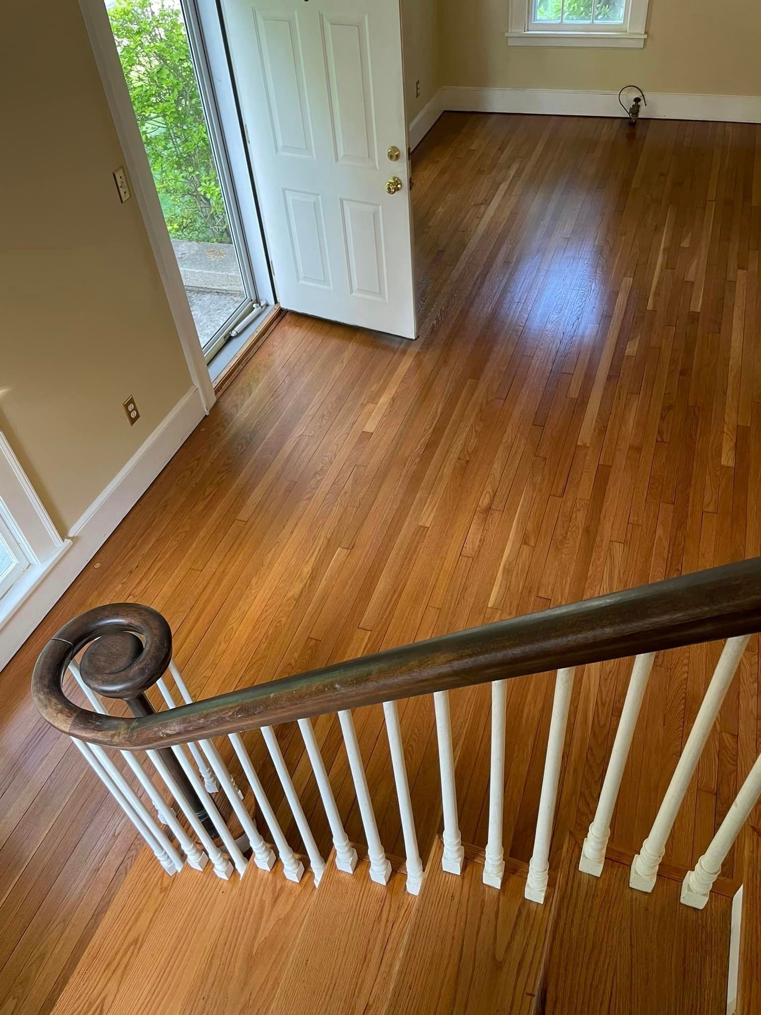 A wooden staircase with a white railing in an empty room.