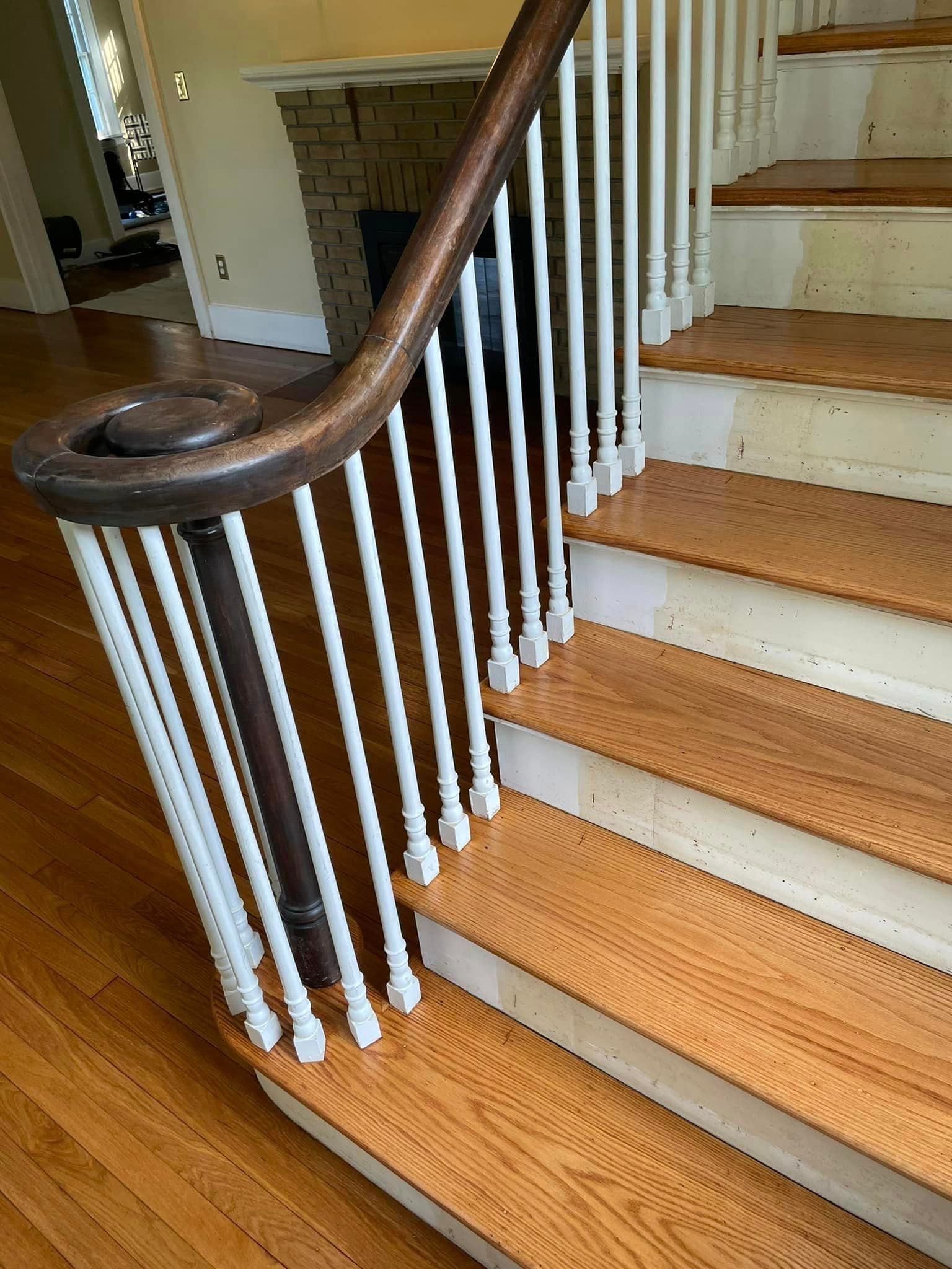 A wooden staircase with white railings and a wooden handrail in a house.