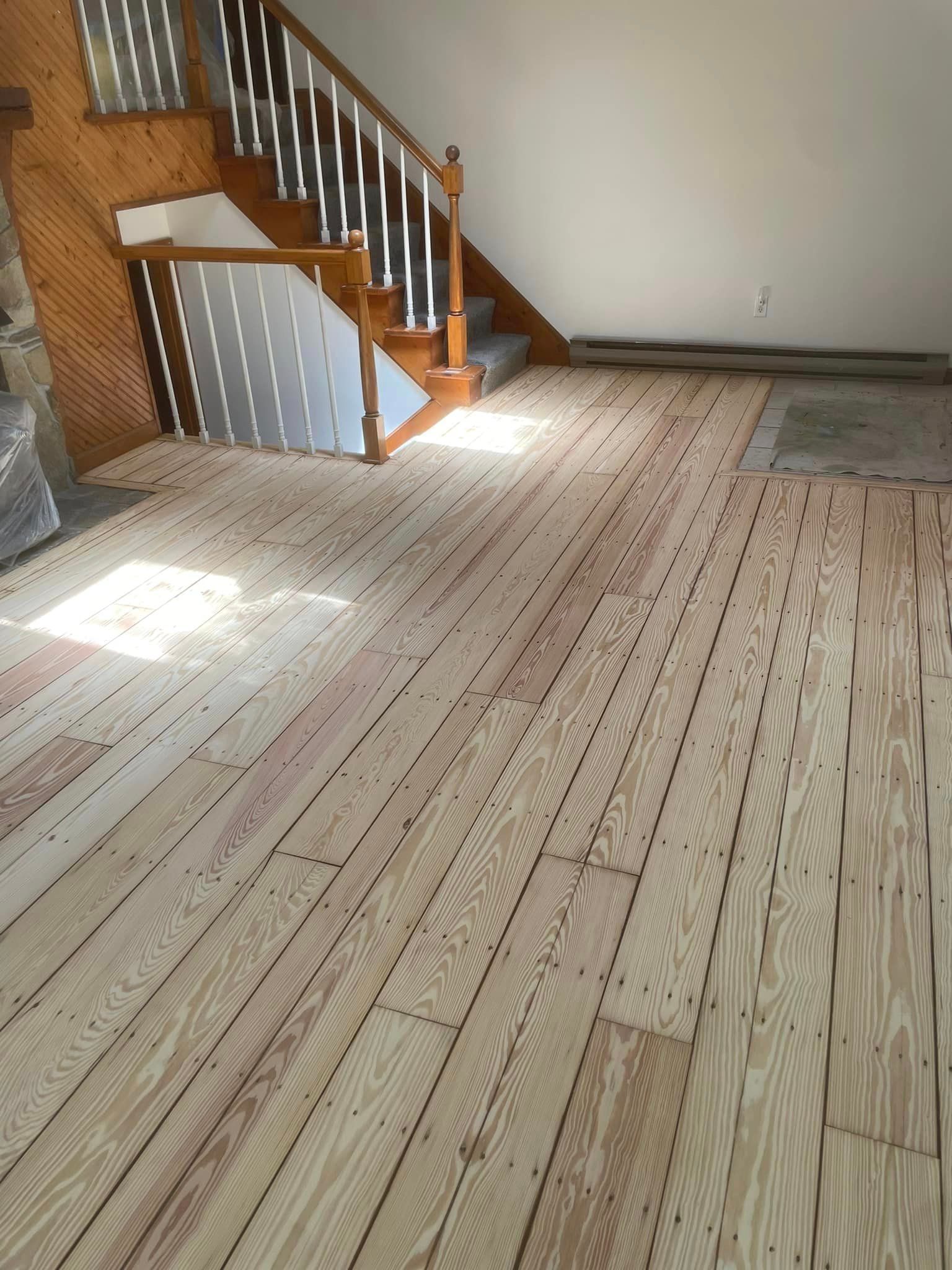 A room with a wooden floor and stairs in the background.