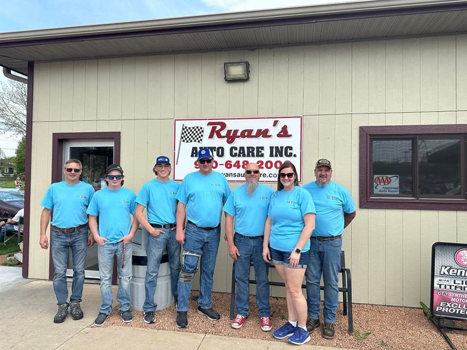Ryan's Auto Care Inc. employees in blue shirts stand in front of the shop. Sign with phone number.