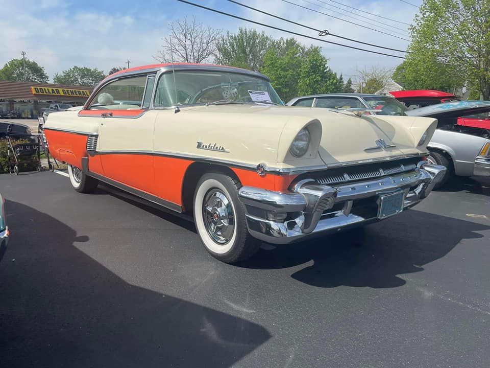 Classic two-tone Mercury Montclair coupe, cream and orange, parked on pavement, sunny day.