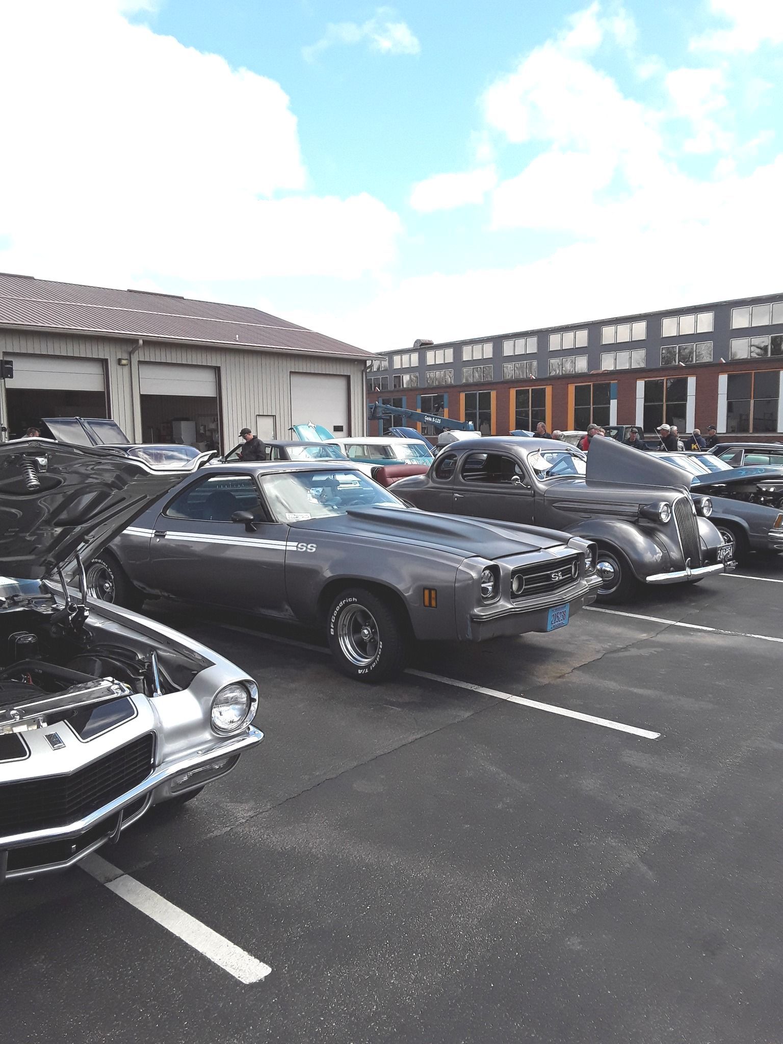 Classic cars parked outside on a sunny day. A gray El Camino is in the foreground.
