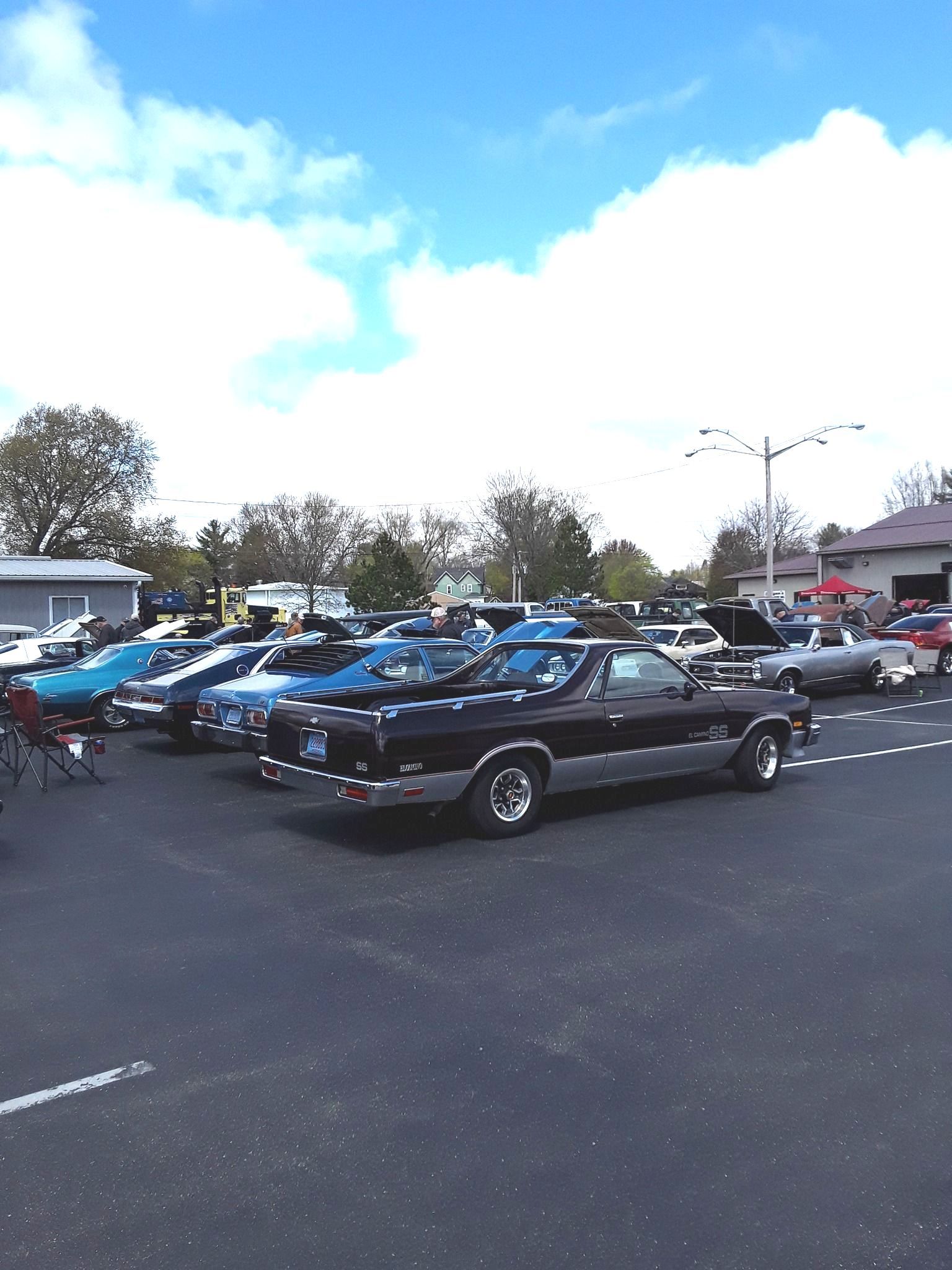 Car show with classic vehicles parked outside on a sunny day.