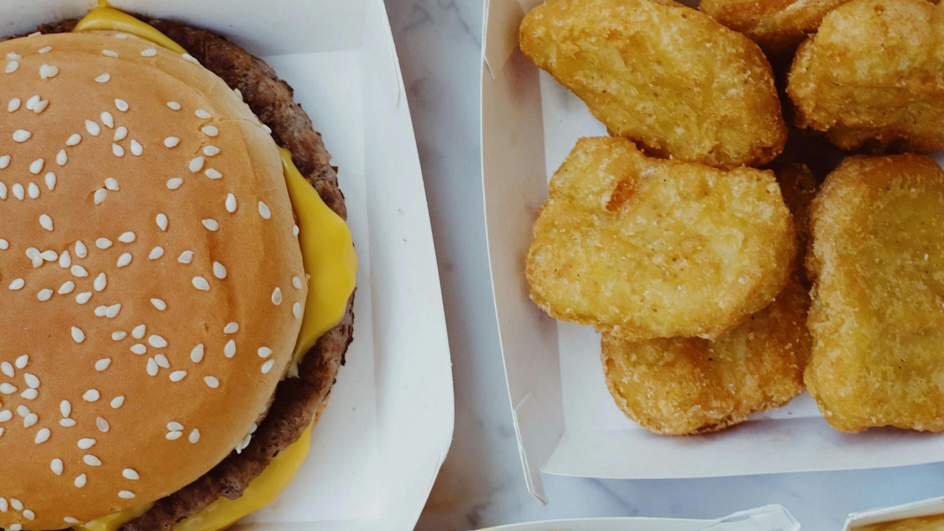 Highly processed takeway cheese burger and chicken nuggets in a takeaway box