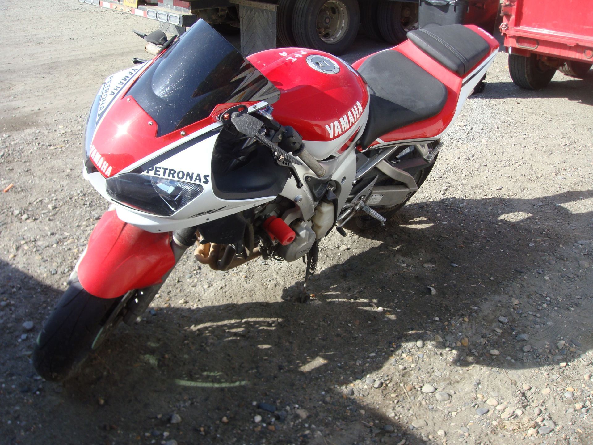 Red sport motorcycle parked on gravel in sunlight